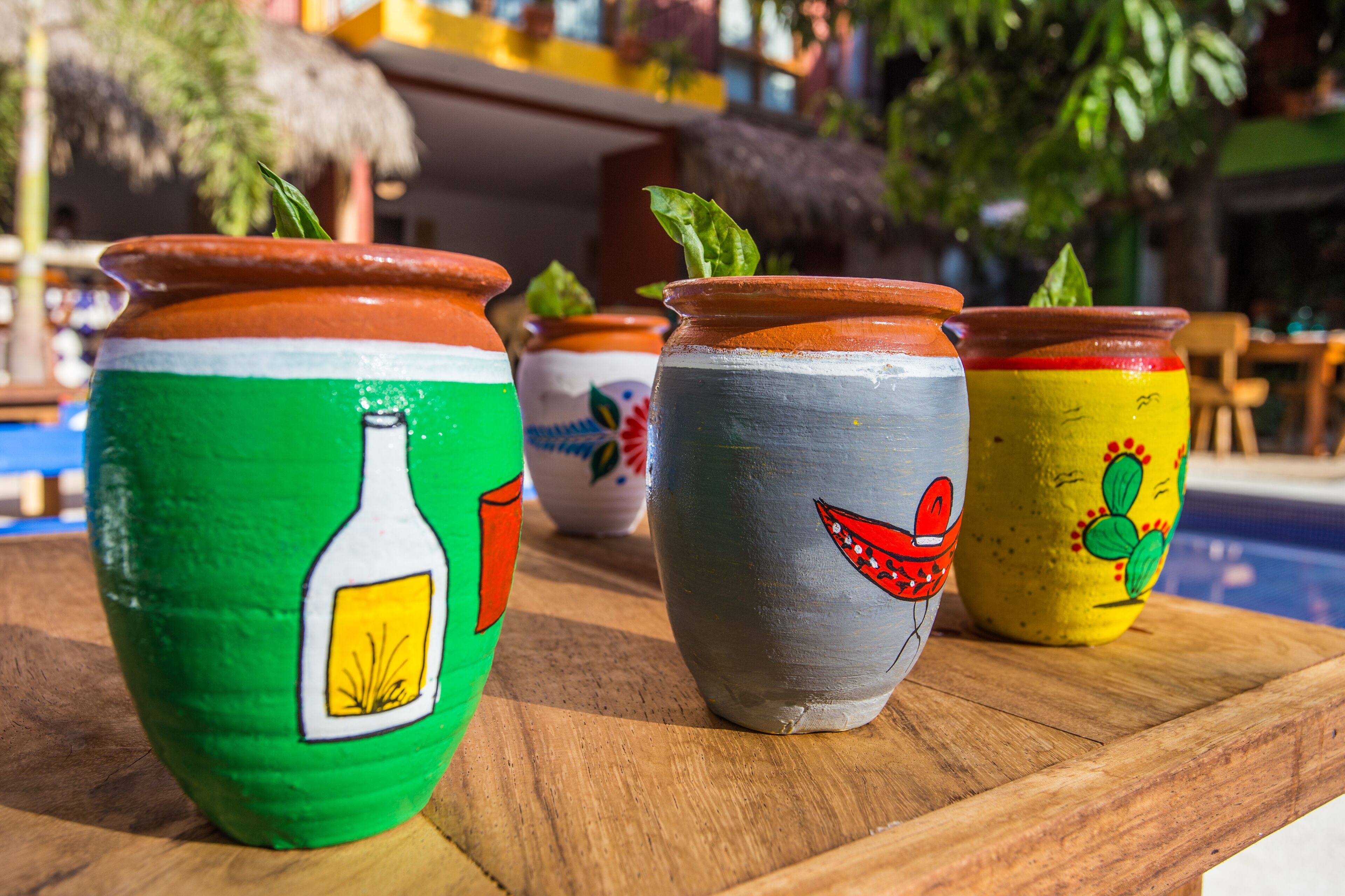Three painted pots with different designs on a wooden surface.