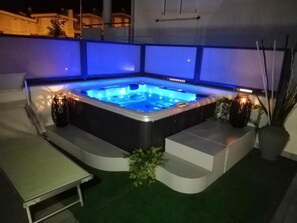 A hot tub with blue lighting, surrounded by steps and potted plants. - Hotel Villa Bianca (San Salvo)