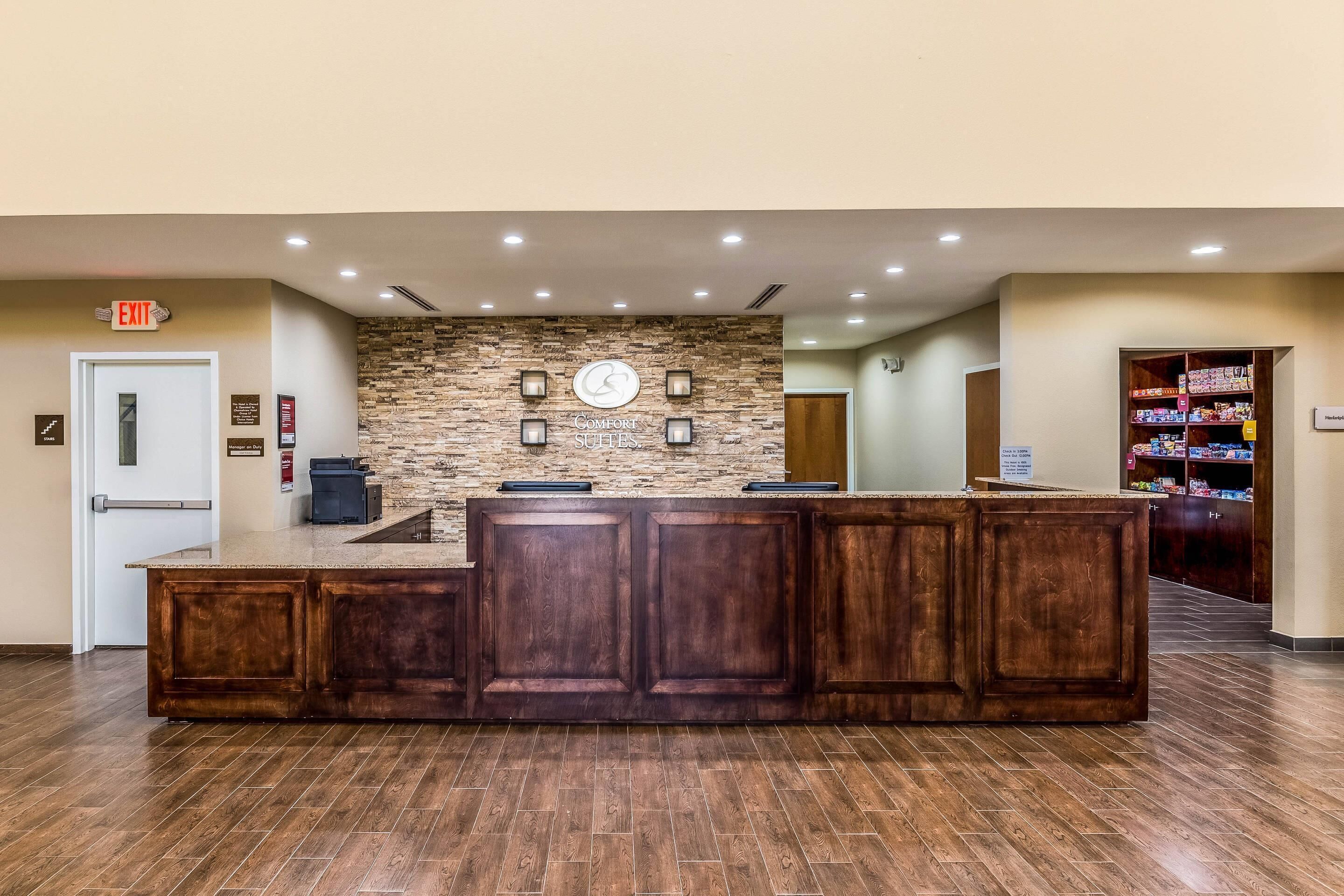 A reception area with a stone wall, wooden reception desk, and a door marked 'EXIT'.