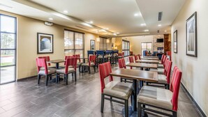 Un vaste espace intérieur aménagé en salle à manger, avec de nombreuses tables et chaises, de grandes fenêtres et un design moderne au niveau du plafond.
