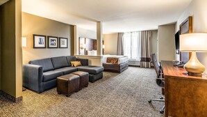 Une chambre d’hôtel avec un canapé, un lit, un bureau et une télévision.
