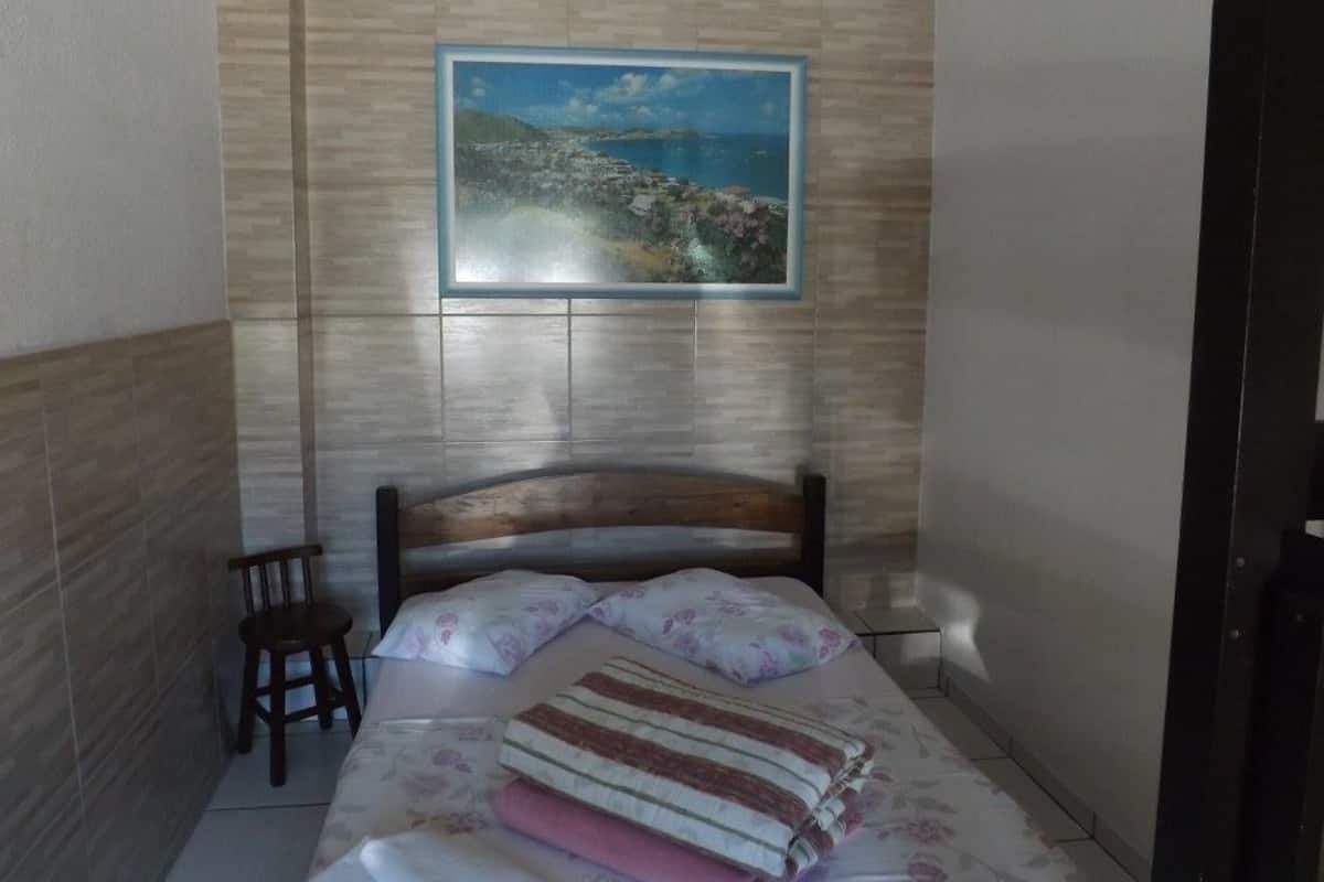 Une chambre à coucher avec un lit, une chaise, un tableau accroché au mur et une tête de lit en bois.
