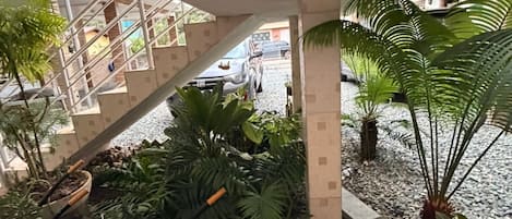 An indoor atrium with a glass ceiling, a staircase, and various potted plants.