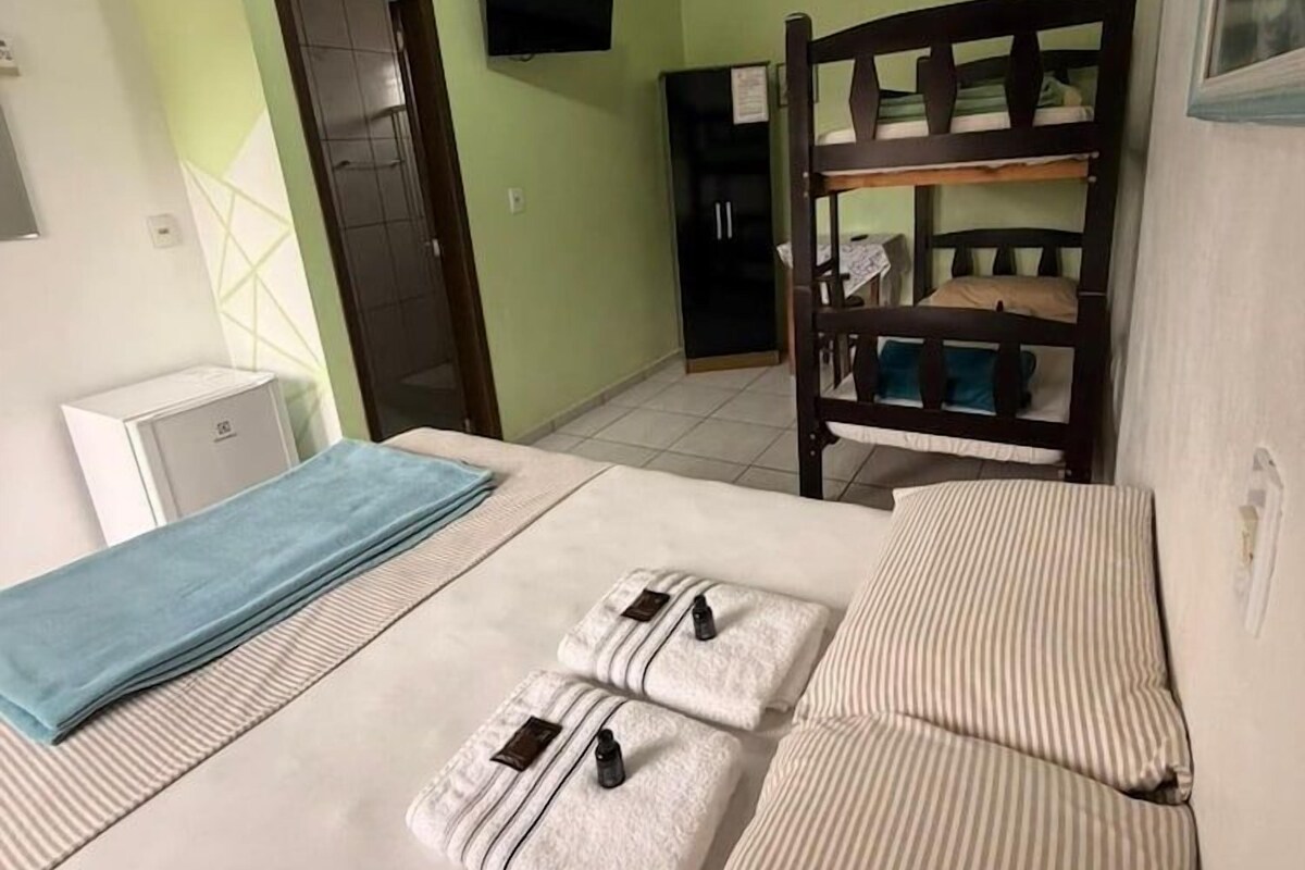 A room with a bunk bed, a desk, a chair, a television, and a door.