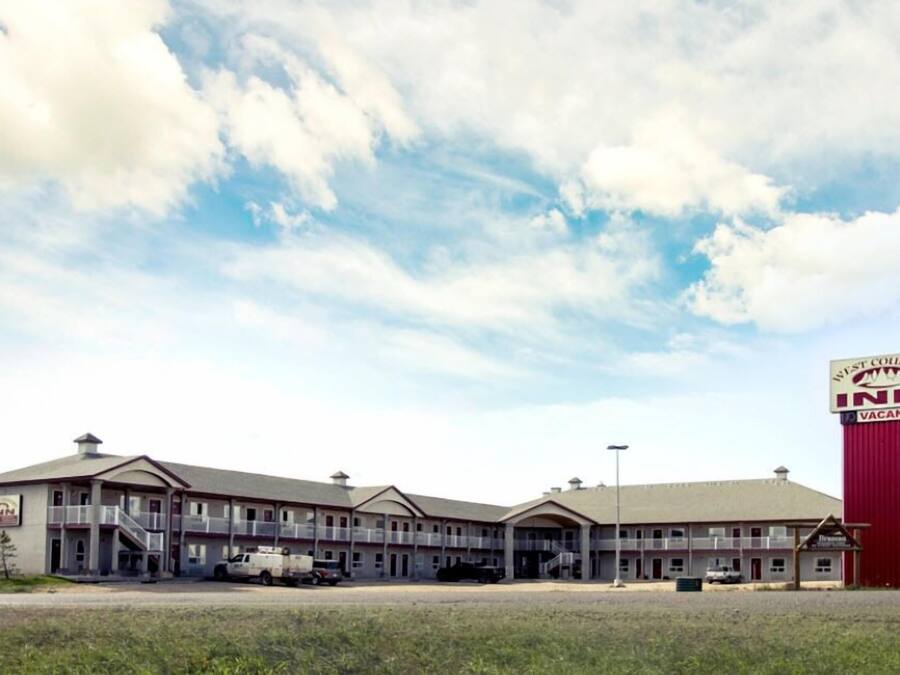 Een herberg in de West Country met een gebouw van twee verdiepingen, een overdekte parkeerplaats en een opvallend rood-wit bord met daop 'beschikbaar'.