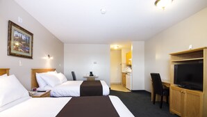 A hotel room with two beds, a desk with a chair, a television, and a kitchenette. - West Country Inn (Drayton Valley)