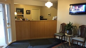 A reception area with a wooden counter, two chairs, a television, and a door marked "EXIT". - West Country Inn (Drayton Valley)