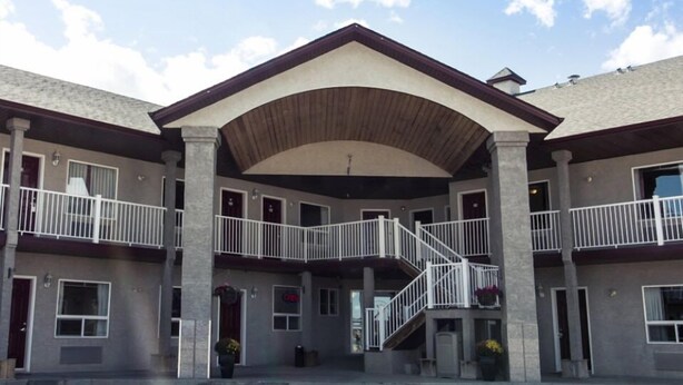 A multi-story building with a central courtyard, balconies, and a staircase leading to the upper floors. - West Country Inn (Drayton Valley)