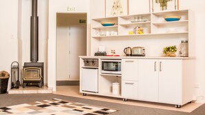 A modern kitchen with a built-in wood stove, white cabinetry, and a microwave. - Abel Tasman Lodge (Marahau)
