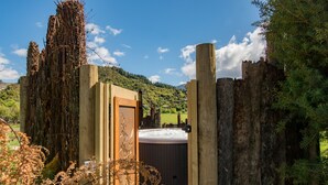A wooden gate leading to a hot tub surrounded by natural scenery. - Abel Tasman Lodge (Marahau)