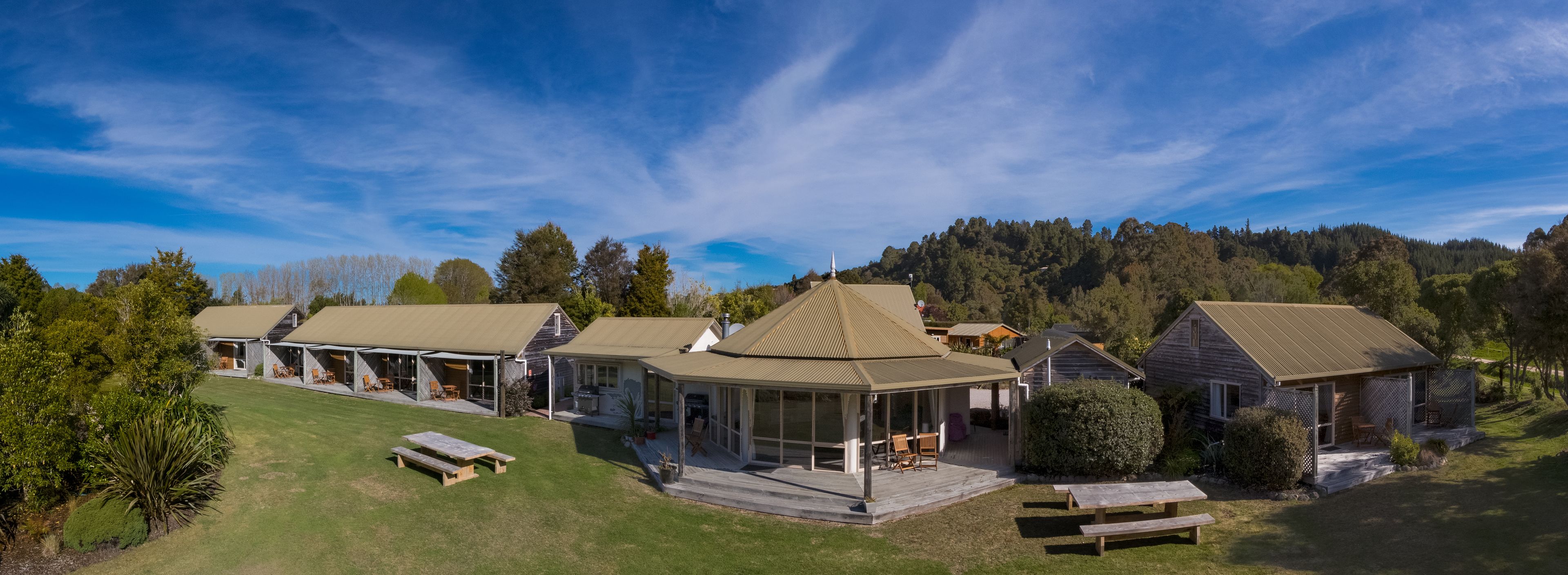 A cluster of cabins with large windows, a covered patio area, and a grassy lawn.