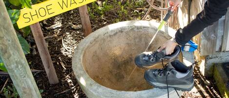 Eine Person wäscht Schuhe in einem Betonbecken, mit einem Schild, auf dem 'SHOE WASH' steht.
