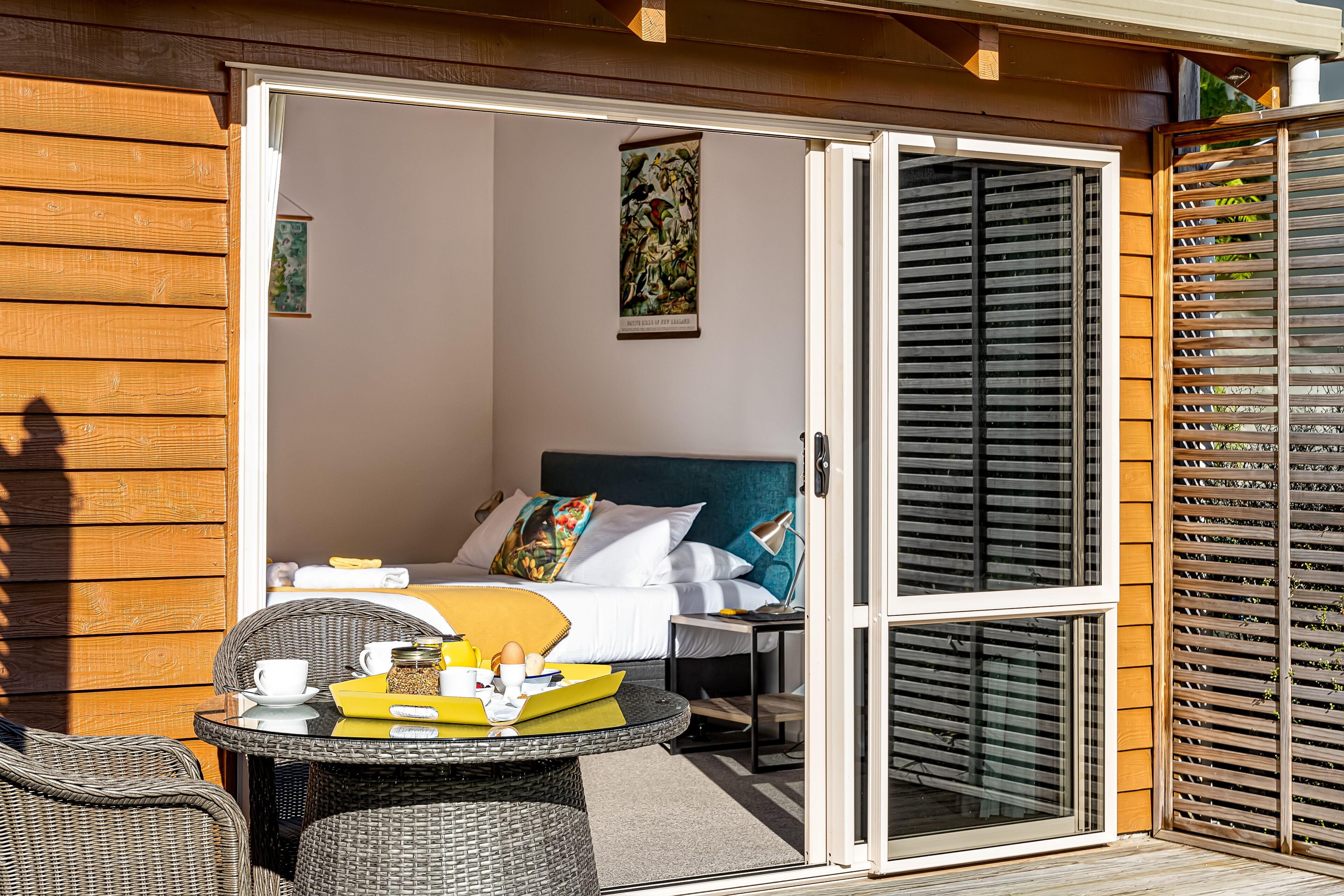 A hotel room with a bed, a table with breakfast items, and a view through a sliding door.