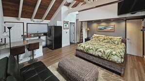 Un dormitorio moderno con una cama grande, un escritorio y una kitchenette.