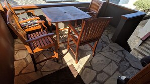 A patio area with a wooden table and chairs, stone flooring, and a small black object on the floor. - Kailua Oceanfront-60' Lap Pool - Upscale Quiet Neighborhood - Legal (Kailua)