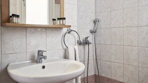 A bathroom with a white sink, a mirror, and a shower. - Favie Suzanne by GHH (Tinos)