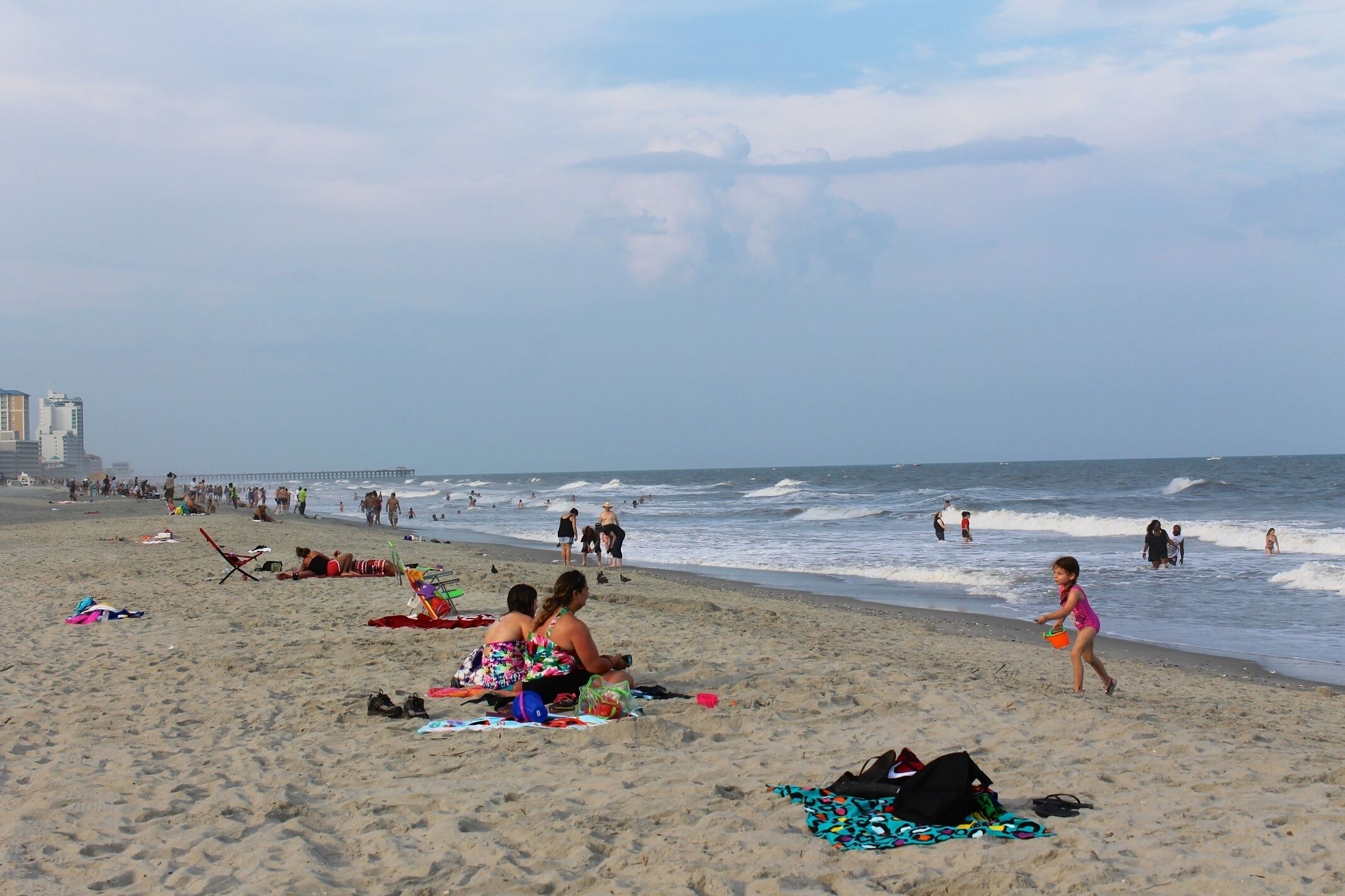 A beach with people relaxing and walking along the shore.