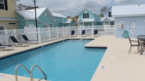 A swimming pool with lounge chairs, a white fence, and a lifeguard stand. - Comfortable and Clean Townhouse, One Block From beach (Myrtle Beach)