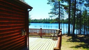 Eine Holzhütte mit einer Terrasse mit Blick auf einen See.