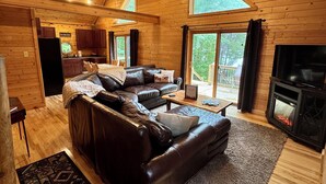 Ein gemütliches Blockhaus-Interieur mit einer großen Ledersofa, einem Kamin und einem Essbereich.