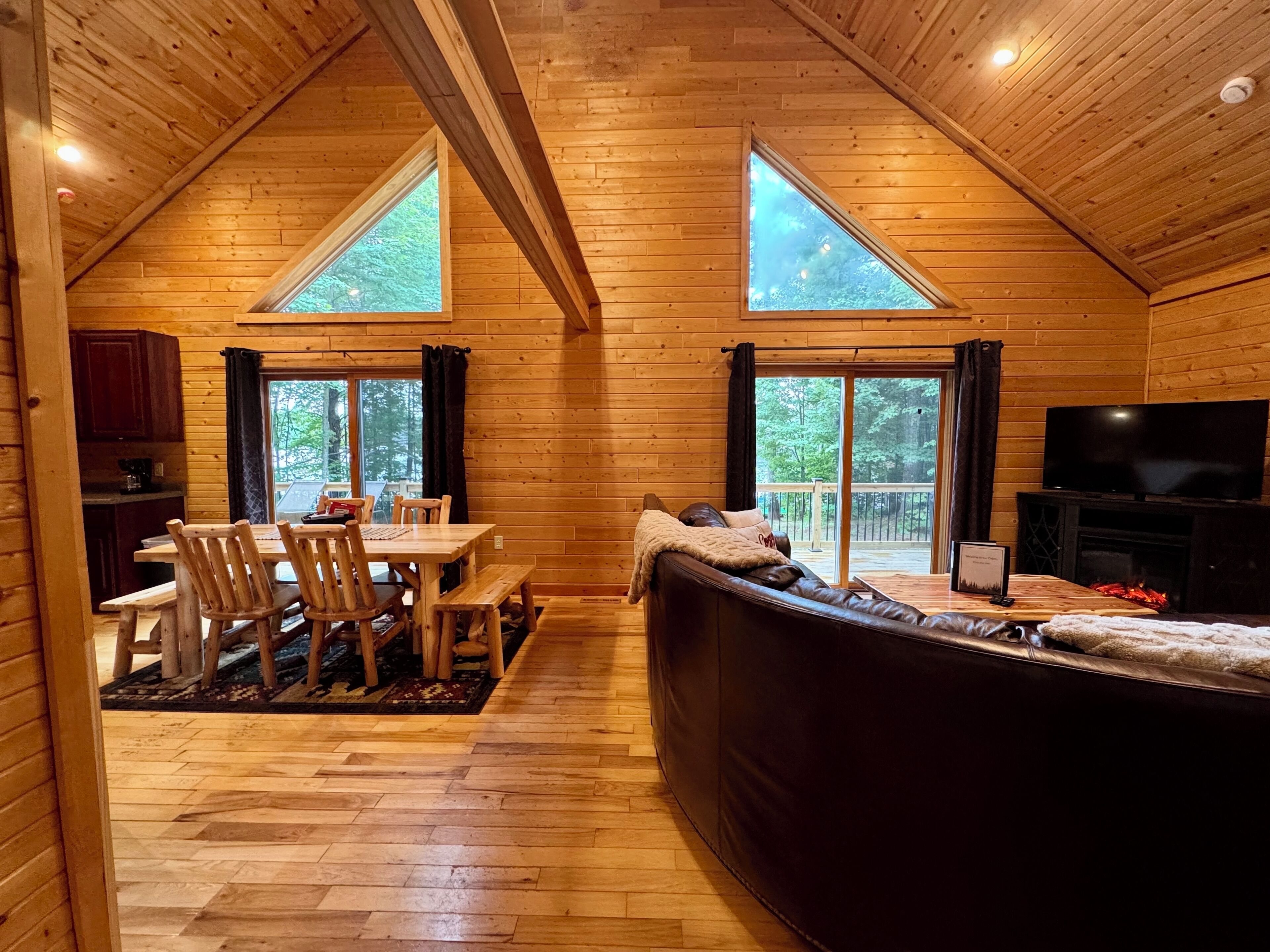 A cozy cabin interior with a dining area, a sofa, and a TV.