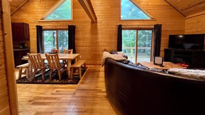 Ein gemütliches Blockhaushaus-Interieur mit Essbereich, einer Couch und einem Fernseher.