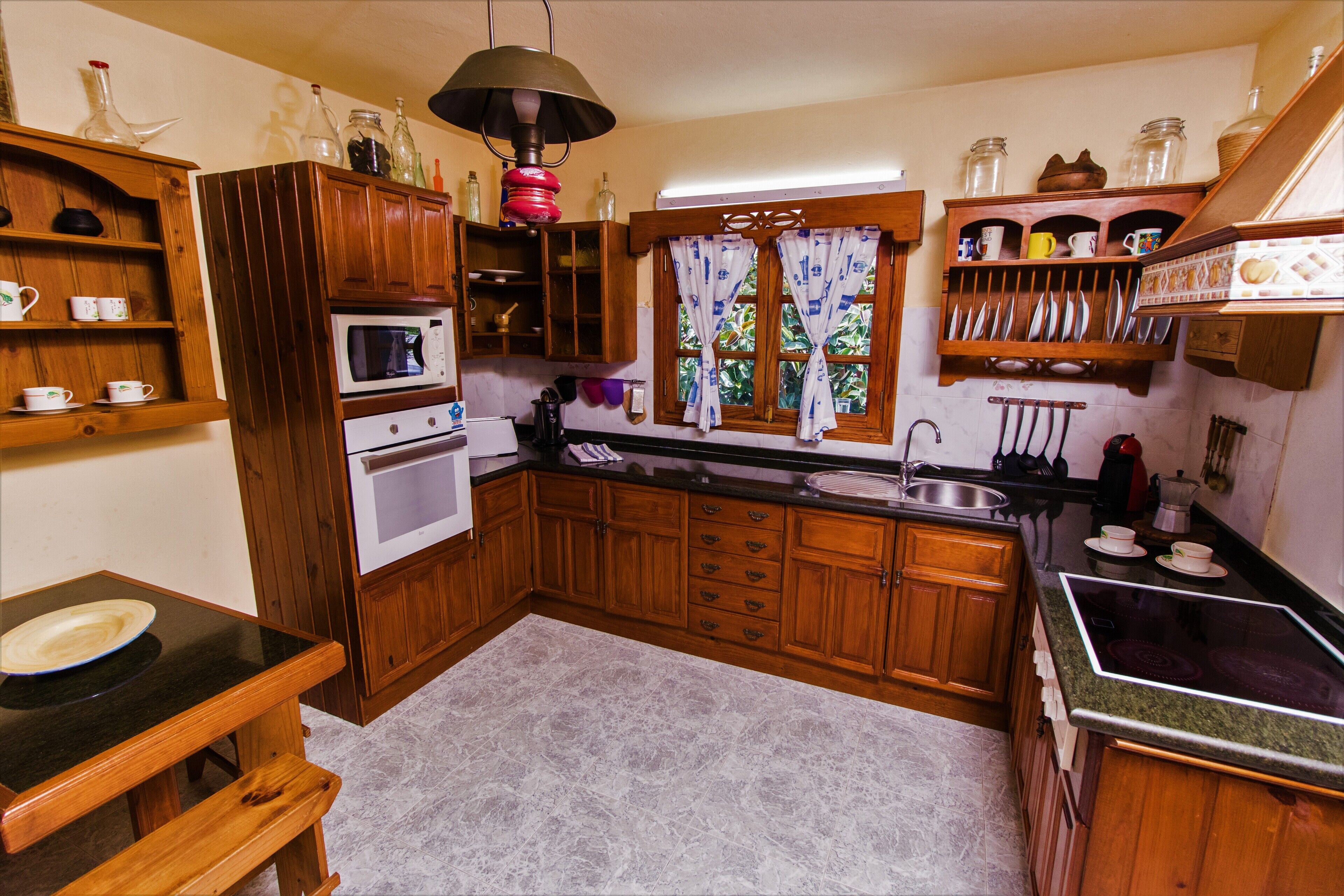 Una cocina con armarios de madera, microondas, horno, lavaplatos y estufa.