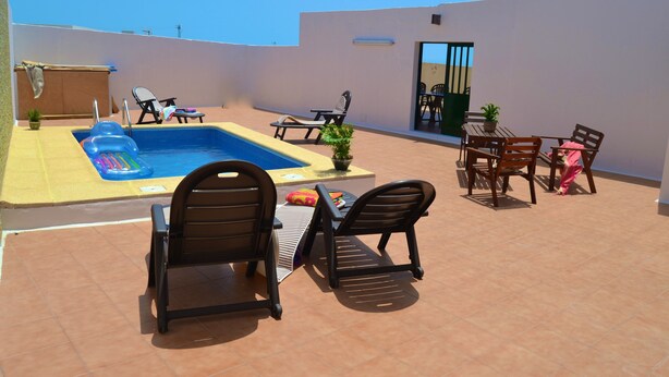 Een terras op het dak met een zwembad, lounge stoelen, een tafel en een eethoek.