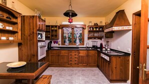 Een keuken met houten kastjes, een magnetron, een spoelbak en een eettafel met een bank.