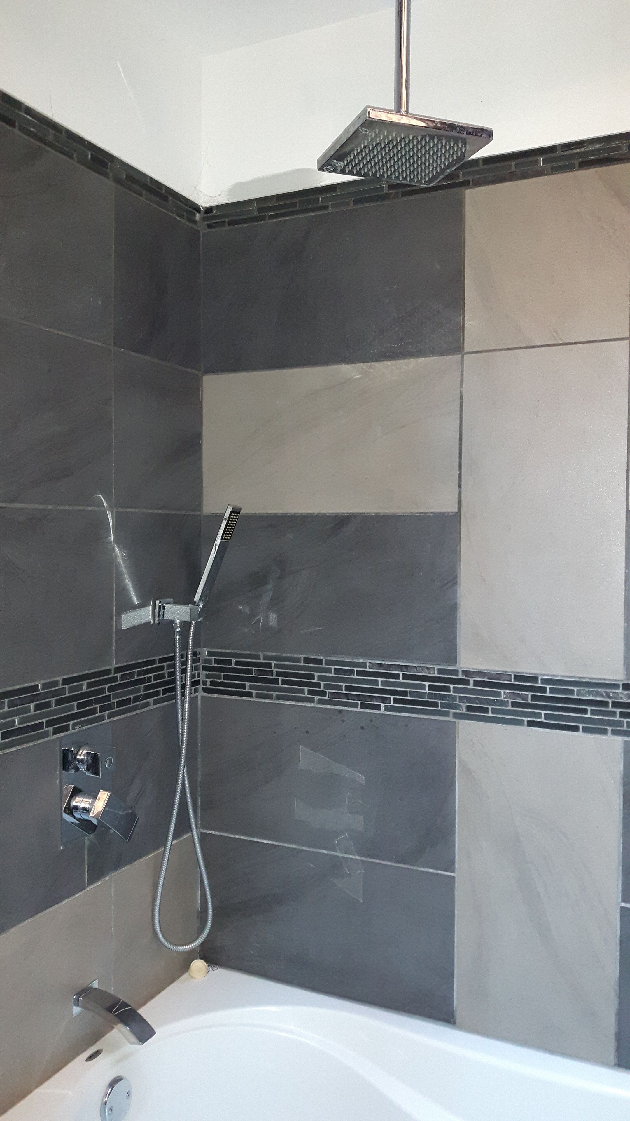 A bathroom with a shower, a bathtub, and a tiled wall.