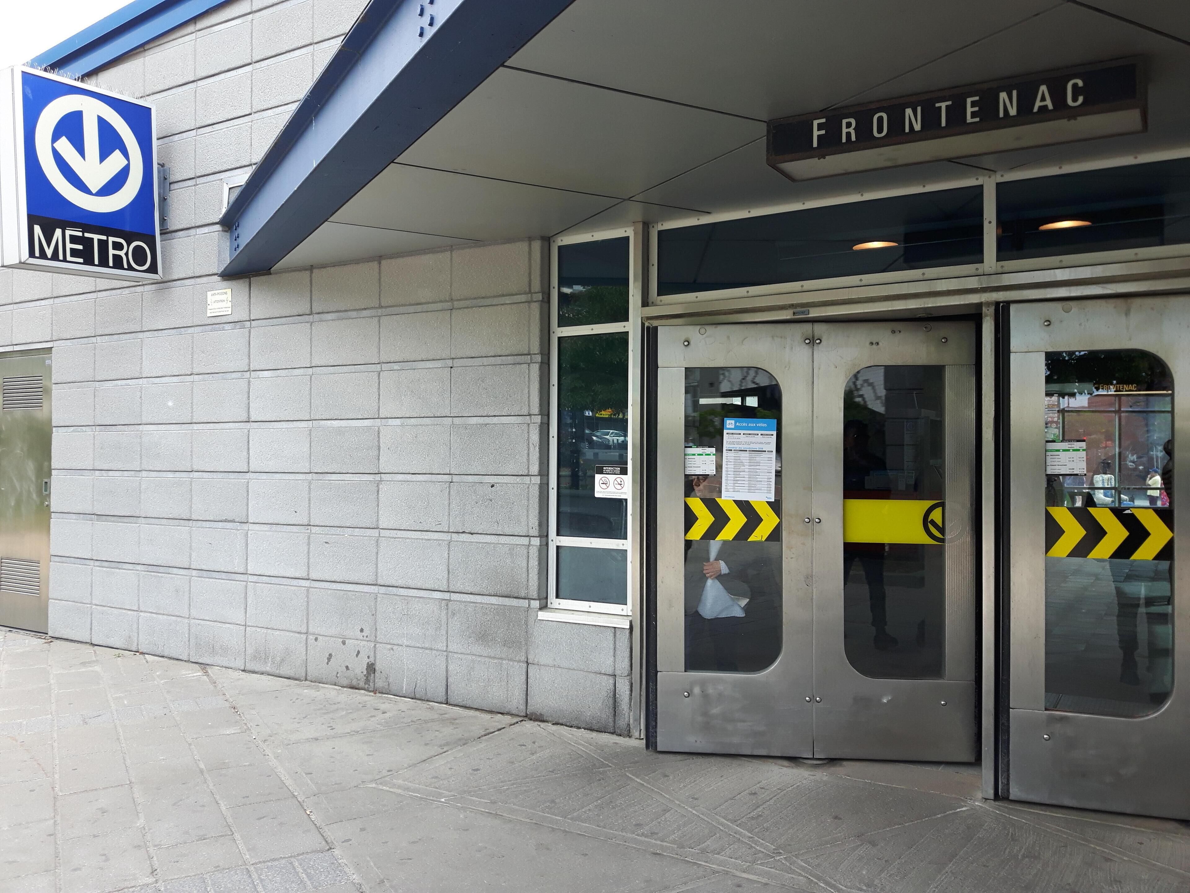 Une entrée de station de métro avec un panneau indiquant la direction à suivre pour accéder au métro.