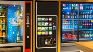A vending machine with various food and drink options, a refrigerator stocked with beverages, and a wooden counter. - Ibis Budget Hamburg Quickborn (Quickborn)