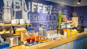 A buffet counter with various food items, utensils, and condiments. - Ibis Budget Hamburg Quickborn (Quickborn)