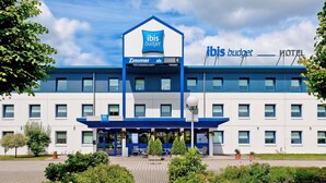 A modern hotel with a prominent 'ibis budget' sign, a covered entrance, and a landscaped front area. - Ibis Budget Hamburg Quickborn (Quickborn)