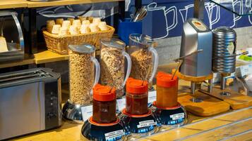 Zona de buffet con diferentes opciones de comida, como cereales, granola y salsas.
