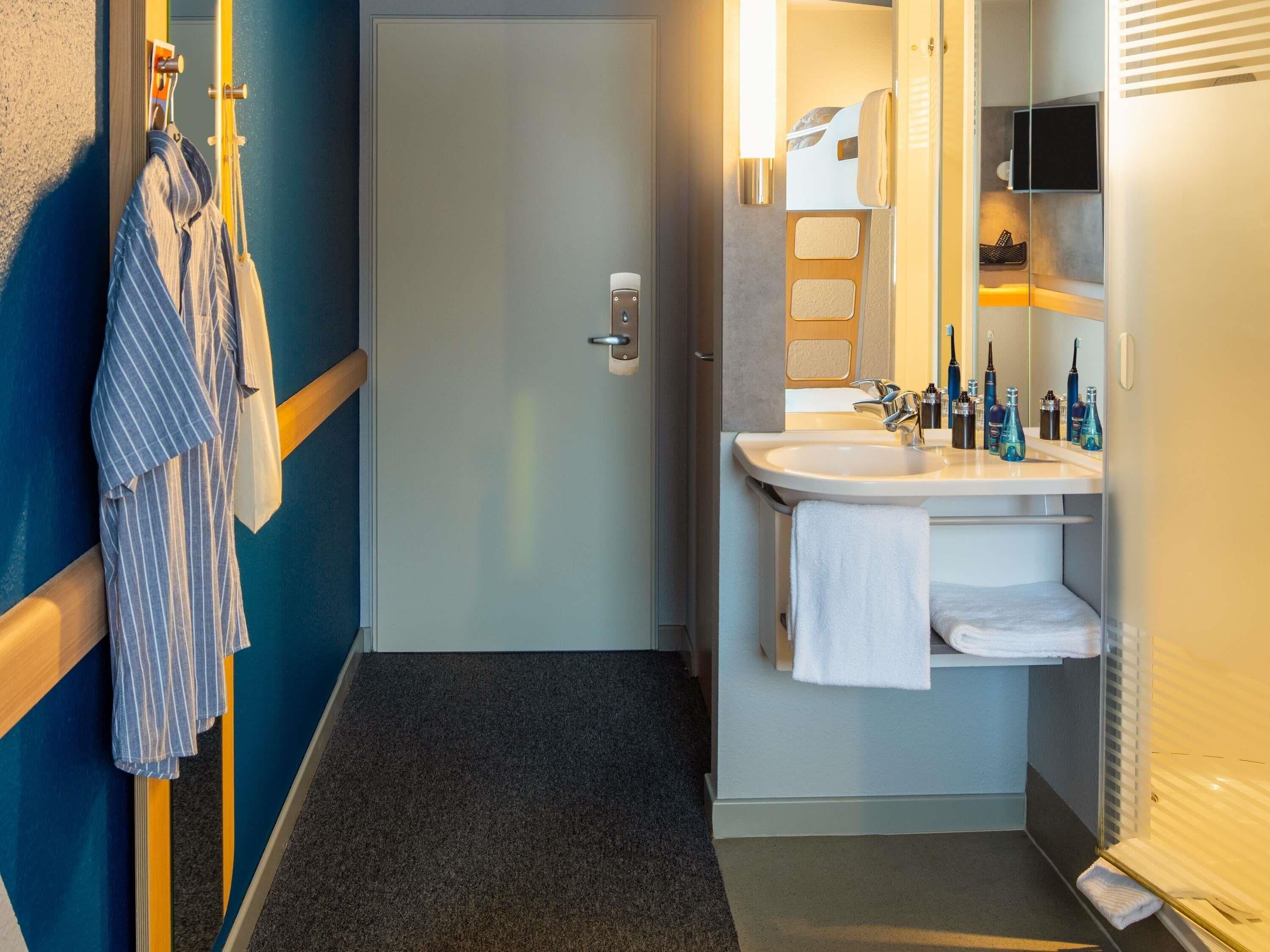 A hotel bathroom with a sink, mirror, and towel rack.