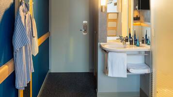 A hotel bathroom with a sink, mirror, and towel rack.