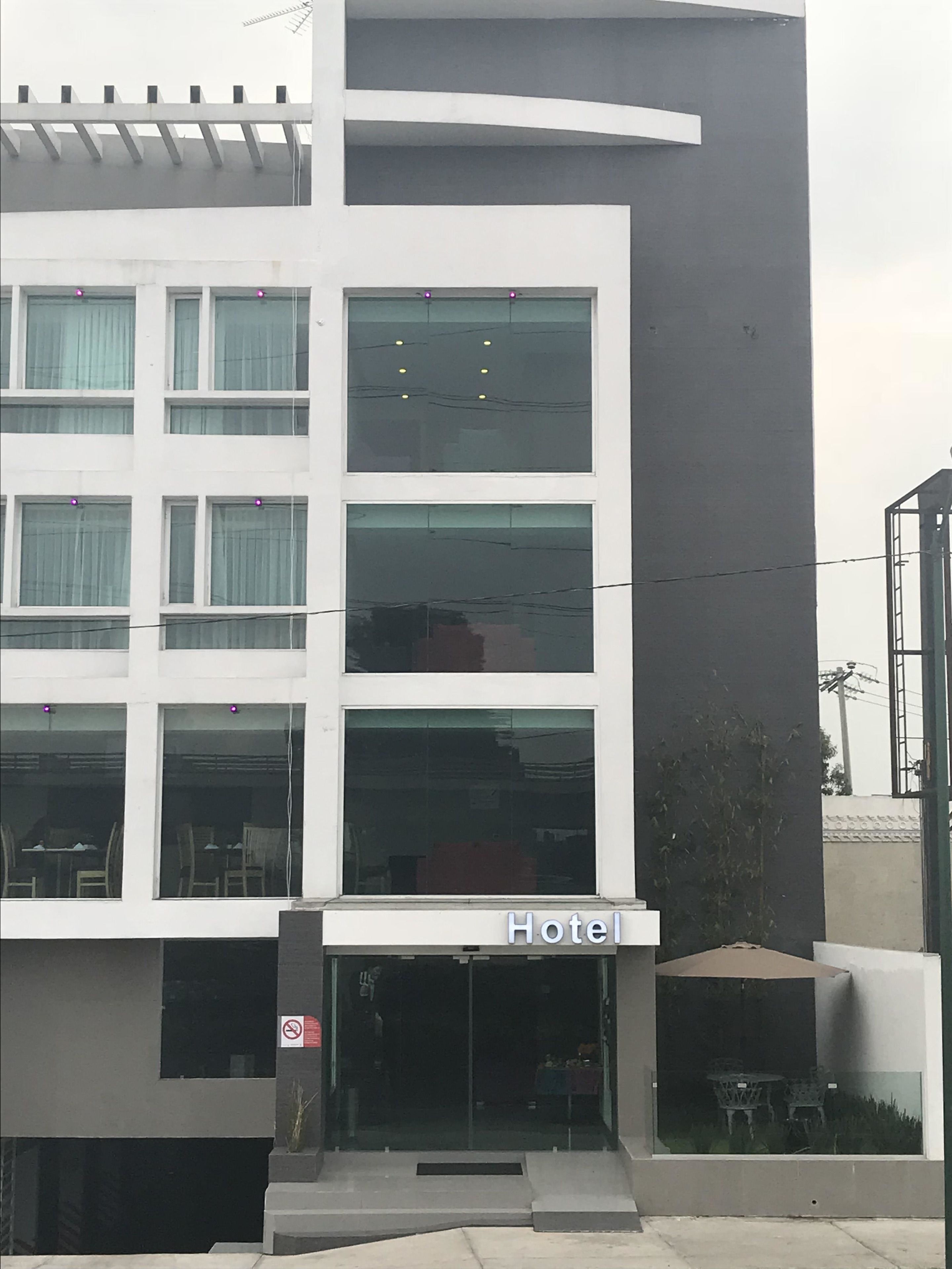 A modern hotel building with a flat facade, large windows, and a sign that reads "Hotel".