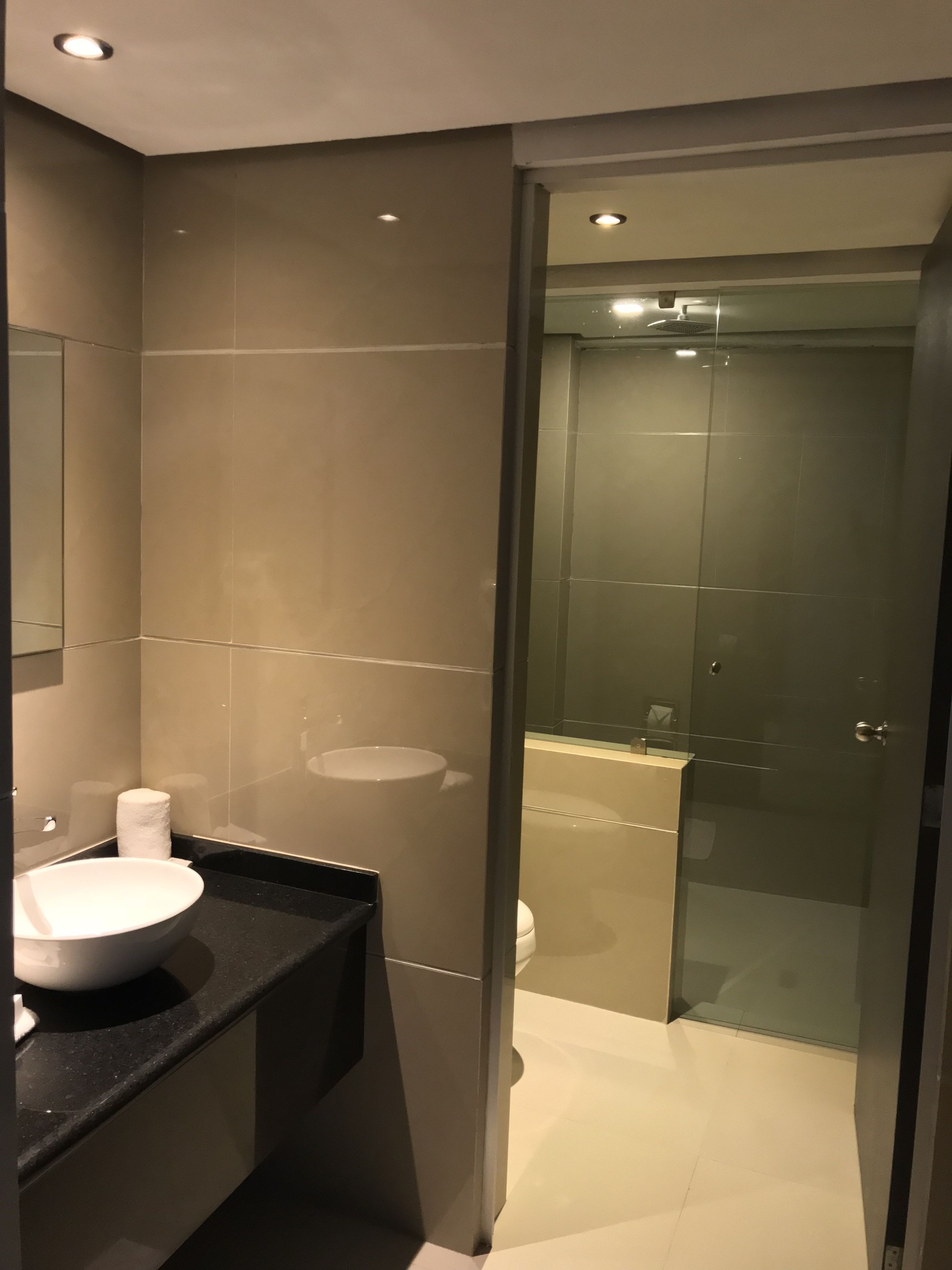 A modern bathroom with a large mirror, a round sink, and a glass-enclosed shower.