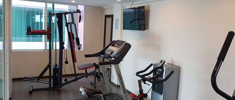 Un gimnasio con cintas de correr, una bicicleta estática y una máquina de pesas.