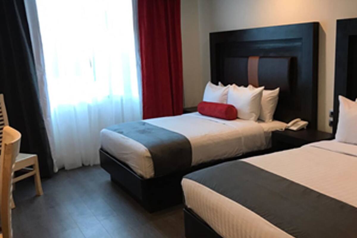 A hotel room with two beds, a chair, and a nightstand with a phone.