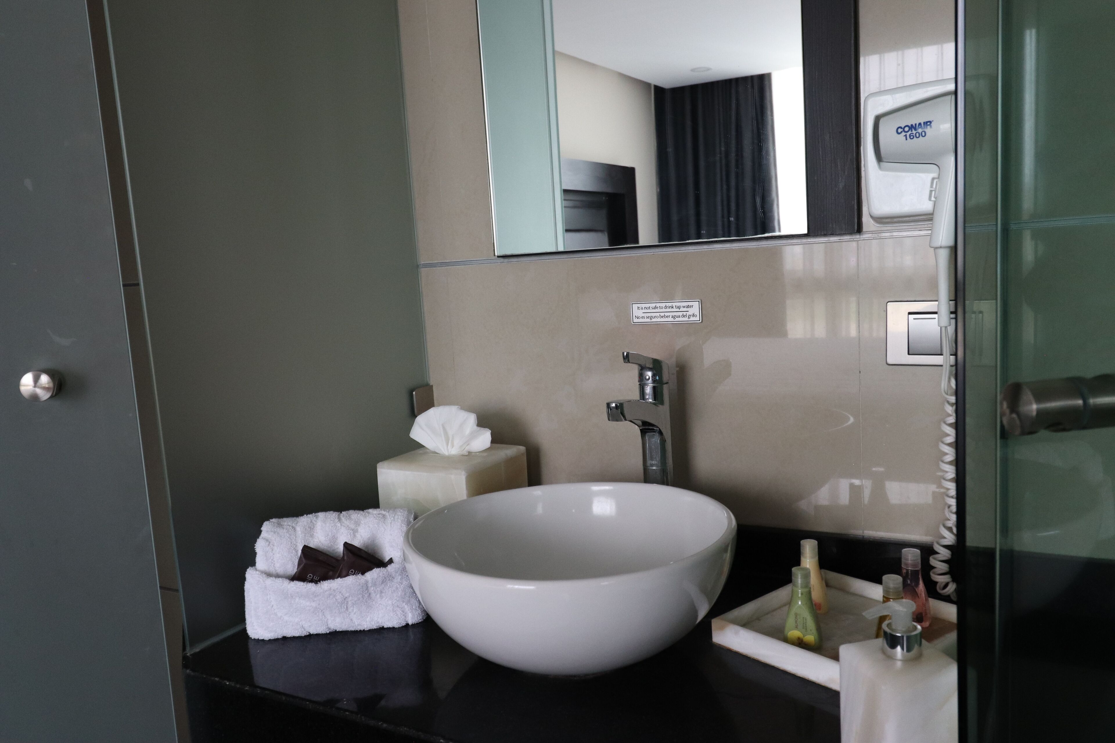 A modern bathroom with a large white sink, a mirror, and a towel rack.