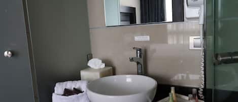 A modern bathroom with a large white sink, a mirror, and a towel rack.