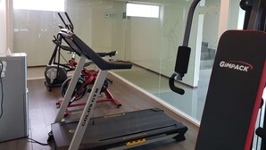 Une salle de sport équipée d’un tapis de course, d’un vélo d’appartement et d’un banc de musculation.