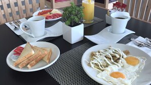 Une table mise pour le petit-déjeuner avec des assiettes de toasts, des œufs et une boisson aux fruits.