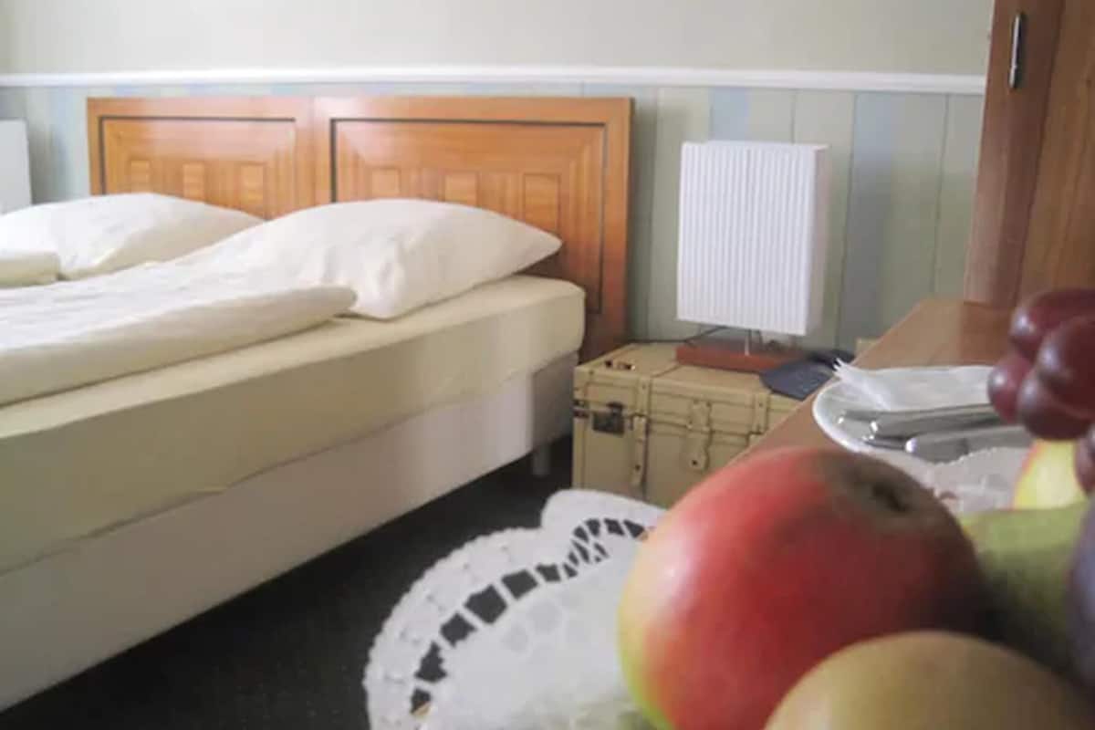 A bedroom with a bed, a suitcase, and a fruit bowl.
