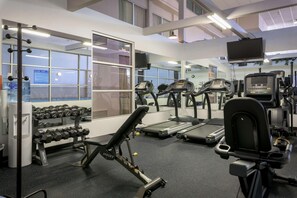 Un gimnasio con cintas de correr, mancuernas y máquinas de pesas.