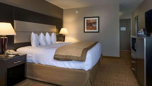 A hotel room with a bed, bedside lamps, a telephone, a television, and a framed picture on the wall. - Ramada by Wyndham Boise (Boise)