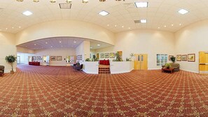 Un hall amplio con alfombra estampada, un mostrador de recepción y obras de arte enmarcadas en las paredes.