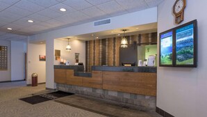 A reception area with a wooden counter, a clock, and a digital weather display. - Ramada by Wyndham Boise (Boise)